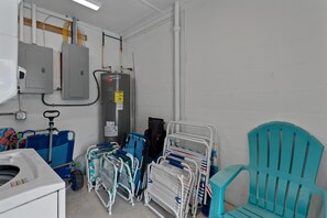 A bathroom with a toilet, sink, and various medical equipment including a blue stretcher, a teal chair, and a white portable bed. - Dune Your Thing A&B (Fort Myers Beach)