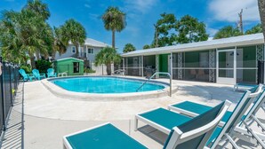 A pool area with lounge chairs, a small building, and palm trees. - Dune Your Thing A&B (Fort Myers Beach)