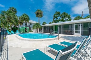 A pool area with lounge chairs, a small building, and palm trees. - Dune Your Thing A&B (Fort Myers Beach)