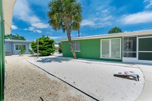 A residential property with a green exterior, a palm tree, and a gravel driveway. - Dune Your Thing A&B (Fort Myers Beach)