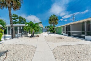 A courtyard with a pathway, palm trees, and a building with large windows. - Dune Your Thing A&B (Fort Myers Beach)