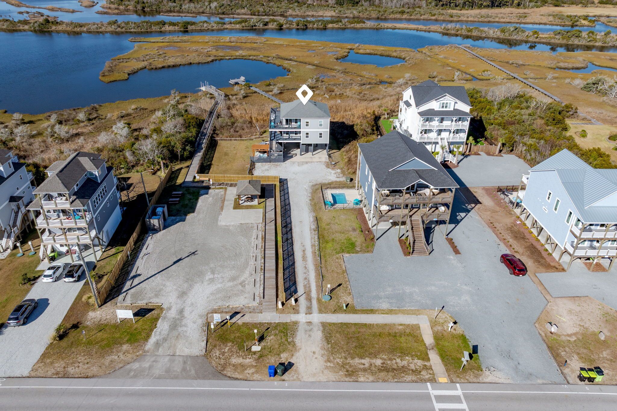 An aerial view of a coastal residential area with houses, a dock, and a marina.