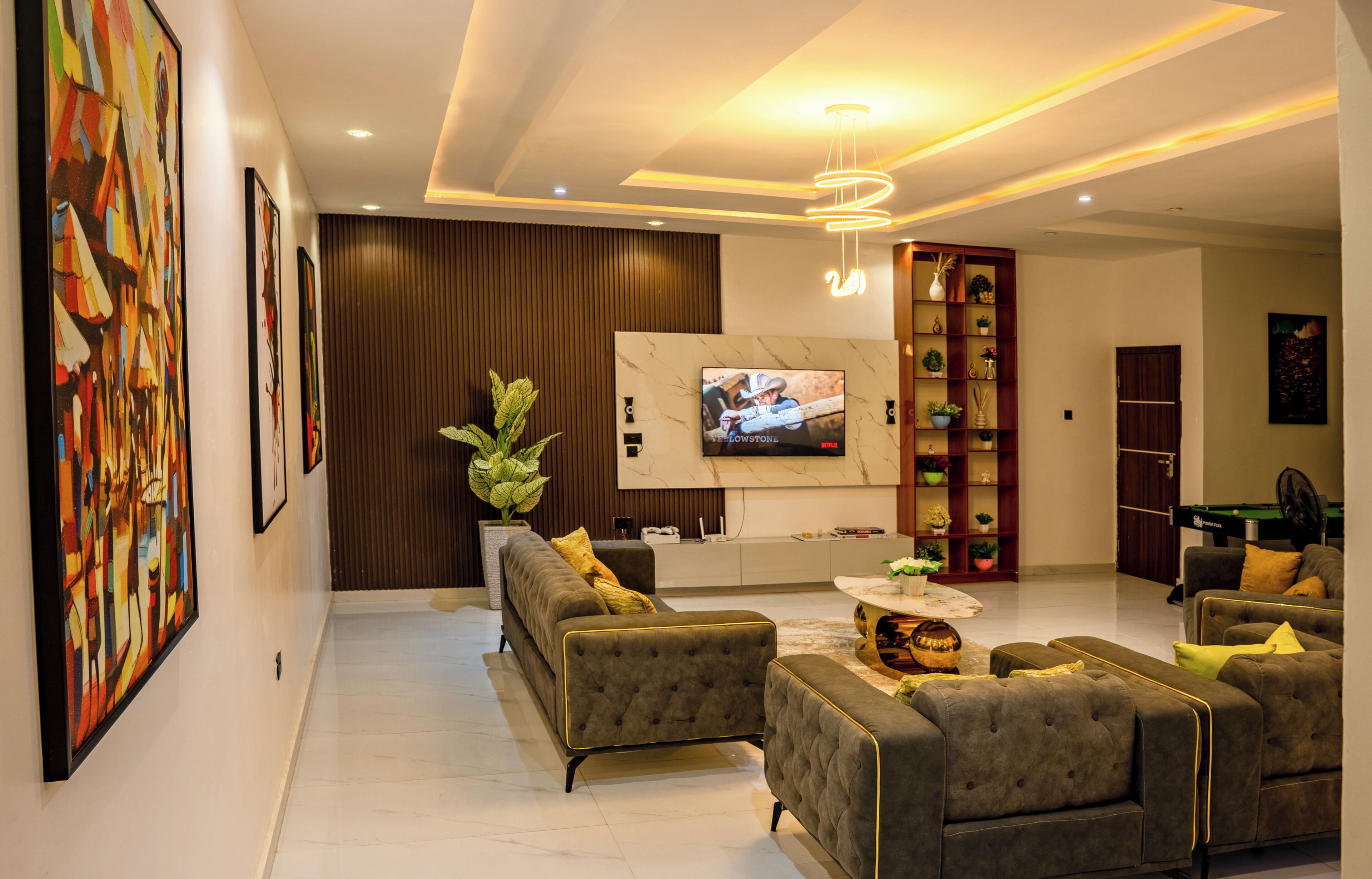 A modern living room with a flat-screen TV, sofas, a coffee table, and a decorative plant.