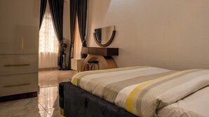Een slaapkamer met een bed, een dressoir, een spiegel en een ventilator.