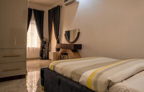 Un dormitorio con cama, cómoda, espejo y ventilador.