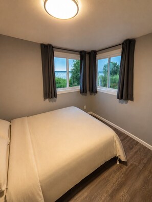 A bedroom with a bed, a window, and curtains.