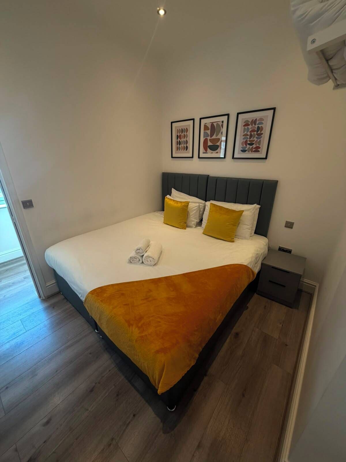 Ein modernes Schlafzimmer mit einem Bett, Nachttischen und Kunstwerken an der Wand.