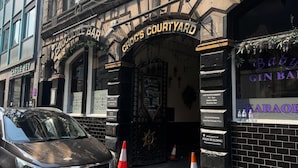 Ein Gebäude mit einem Schild für Croc's Courtyard, eine Karaoke-Bar, und ein geparktes Auto davor.