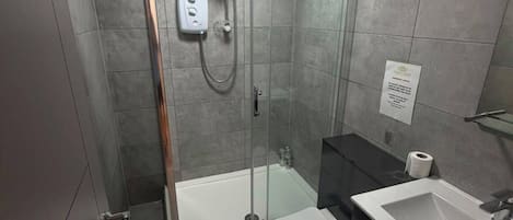 A modern bathroom with a glass-enclosed shower, a white toilet, and a sink.