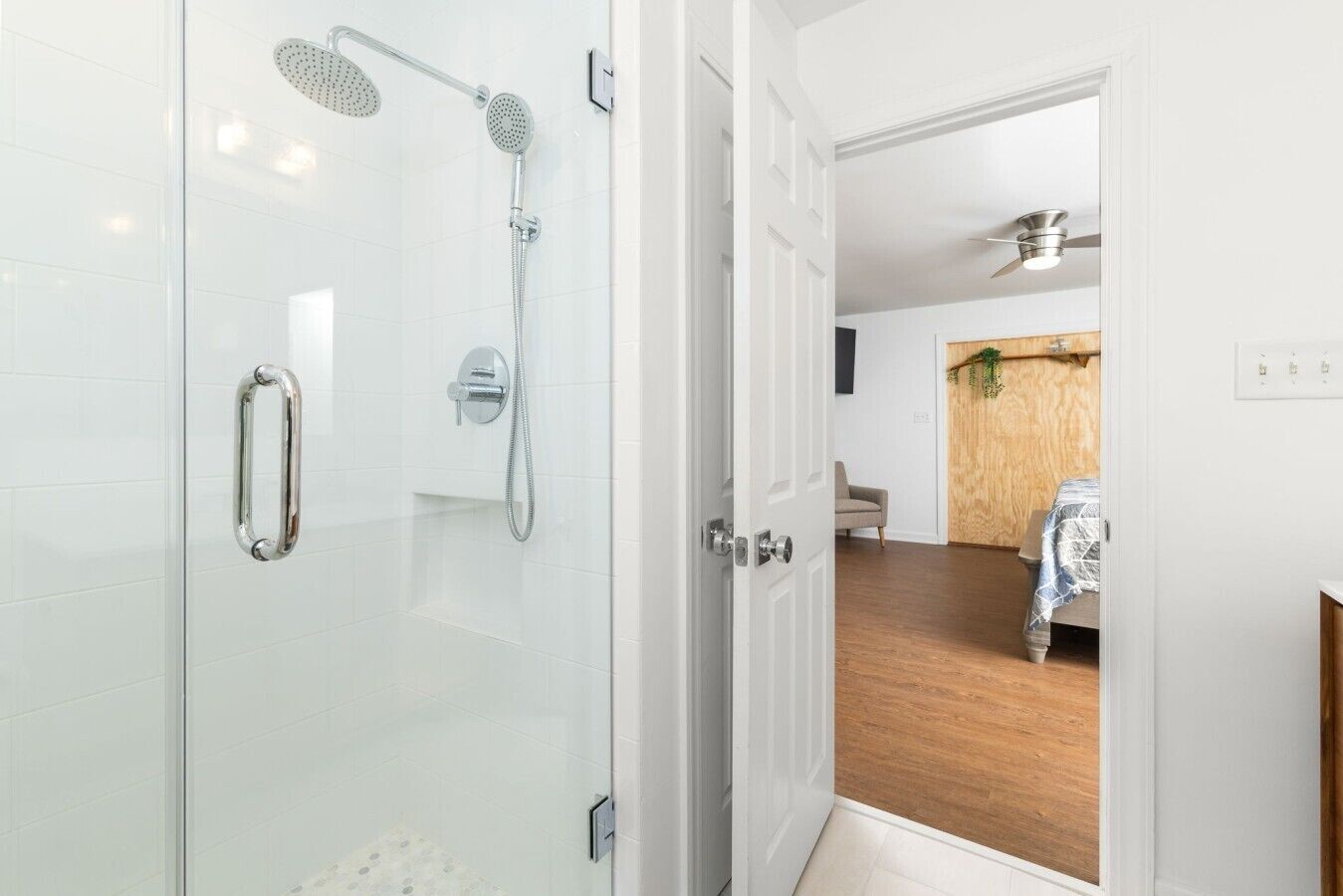 A modern bathroom with a glass shower enclosure, a handheld showerhead, and a wall-mounted faucet.