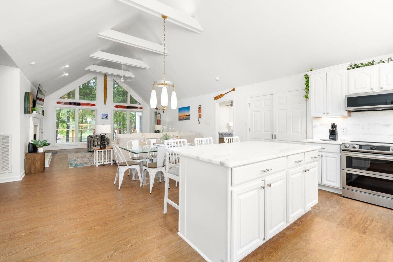 A modern kitchen with white cabinetry, a large island, and a dining area with white chairs.