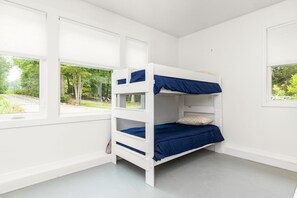 Ein Stockbett in einem Raum mit weißen Wänden und großen Fenstern.