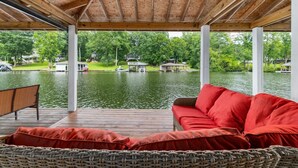 Un espacio de estar techado al aire libre con vistas a un lago y barcos amarrados.