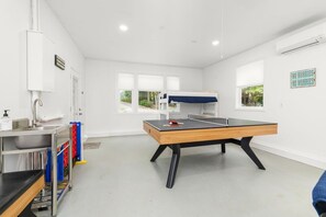A room with a ping pong table, a sink with a soap dispenser, and a bunk bed with a blue cover. - Waters Edge| Boat Lift+Fenced Yard+Kayaks+PingPong (Littleton)
