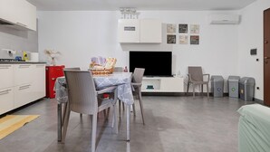A modern kitchen with white cabinets, a red appliance, and a dining area with wicker chairs and a table. - Holiday Home 'Dal Cappellaio Matto' with Private Terrace, Wi-Fi and Air Conditioning (Taranto)