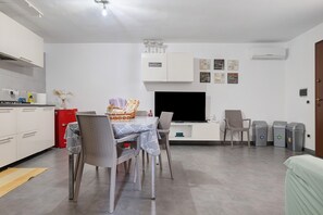 A modern kitchen with white cabinets, a red appliance, and a dining area with wicker chairs and a table.