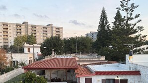 A residential building with a red-tiled roof, stone walls, and a small garden area with a tree and shrubs. - Holiday Home 'Dal Cappellaio Matto' with Private Terrace, Wi-Fi and Air Conditioning (Taranto)