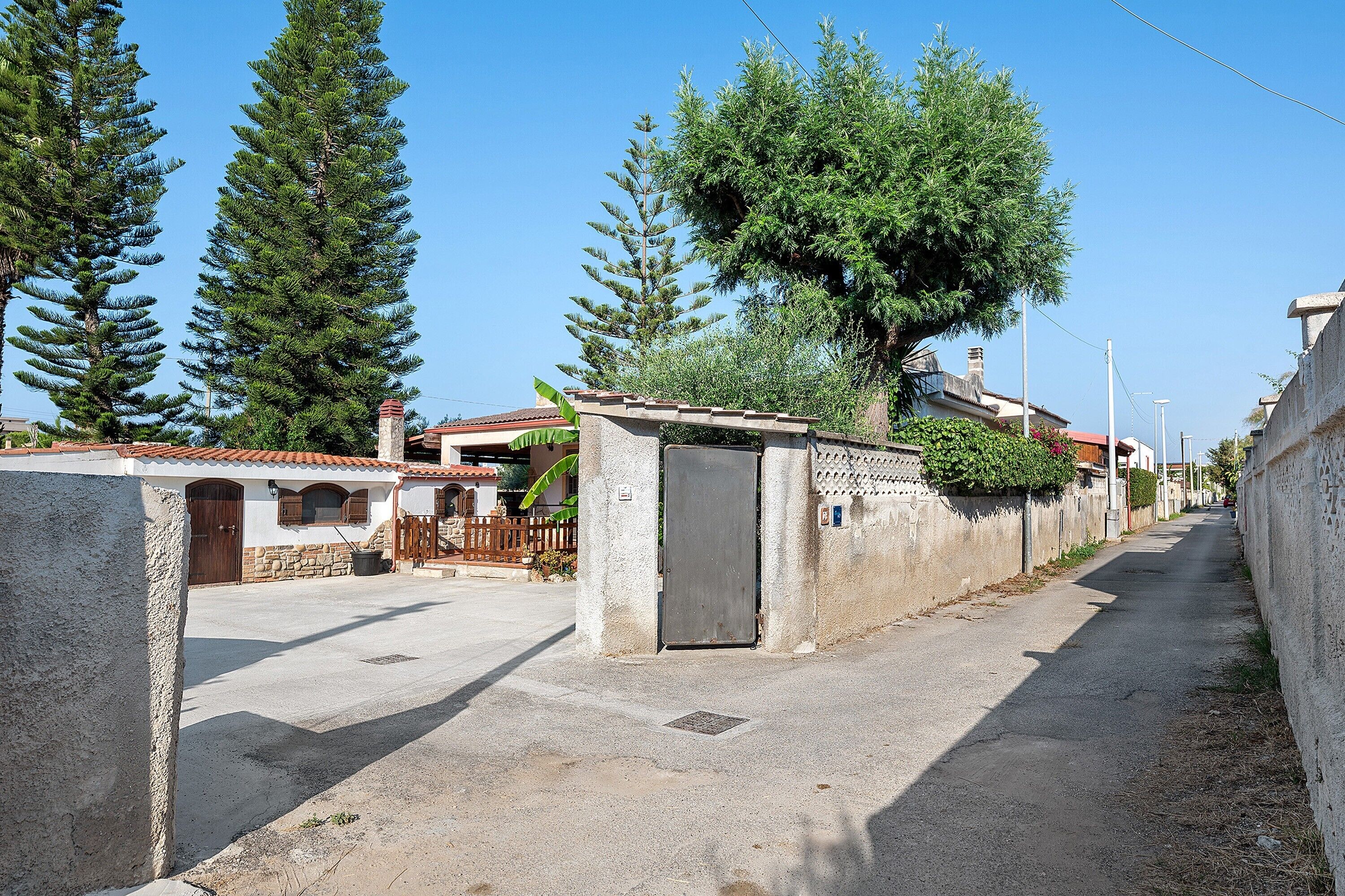 A residential street with houses, a paved road, and a clear sky.