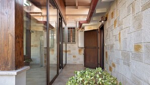 A narrow corridor with glass doors leading to a room, a wooden door, and a stone wall. - Holiday Home 'Dal Cappellaio Matto' with Private Terrace, Wi-Fi and Air Conditioning (Taranto)