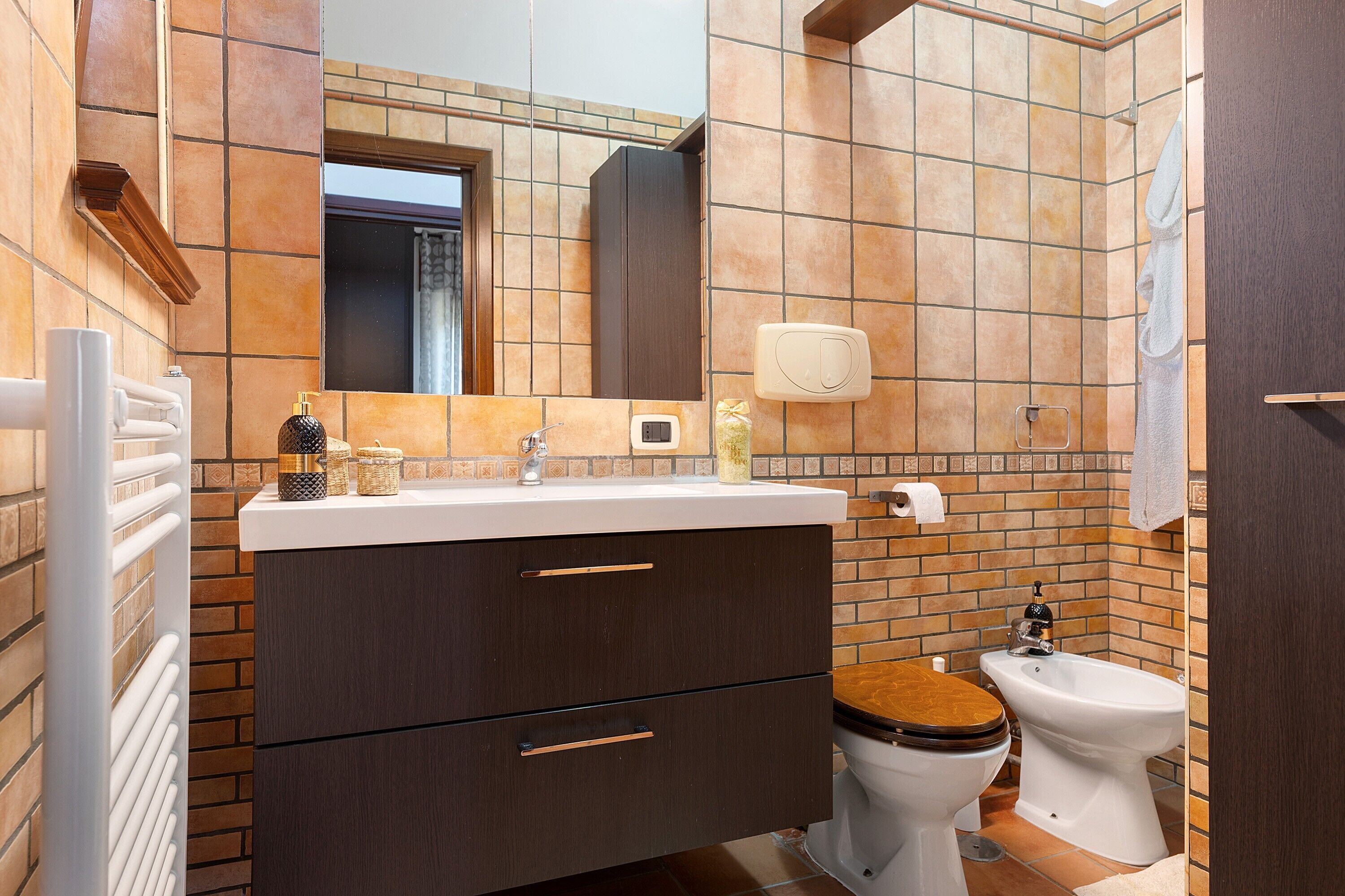 Un bagno con un lavabo, un water, uno specchio e un portasciugamani.
