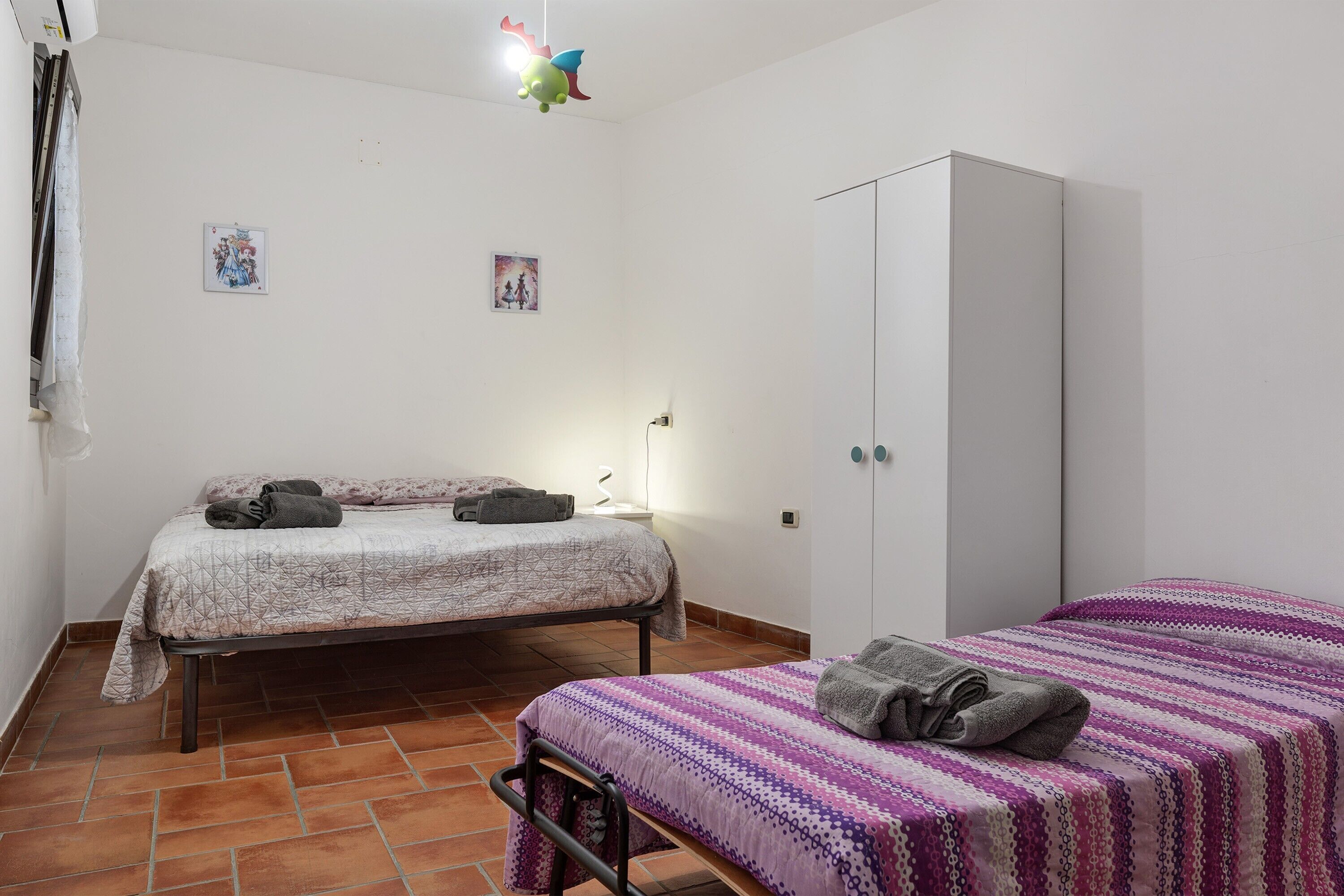 Une chambre avec deux lits, une armoire et une petite table de chevet.