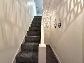 Una scala con gradini rivestiti di moquette e un muro bianco su un lato.