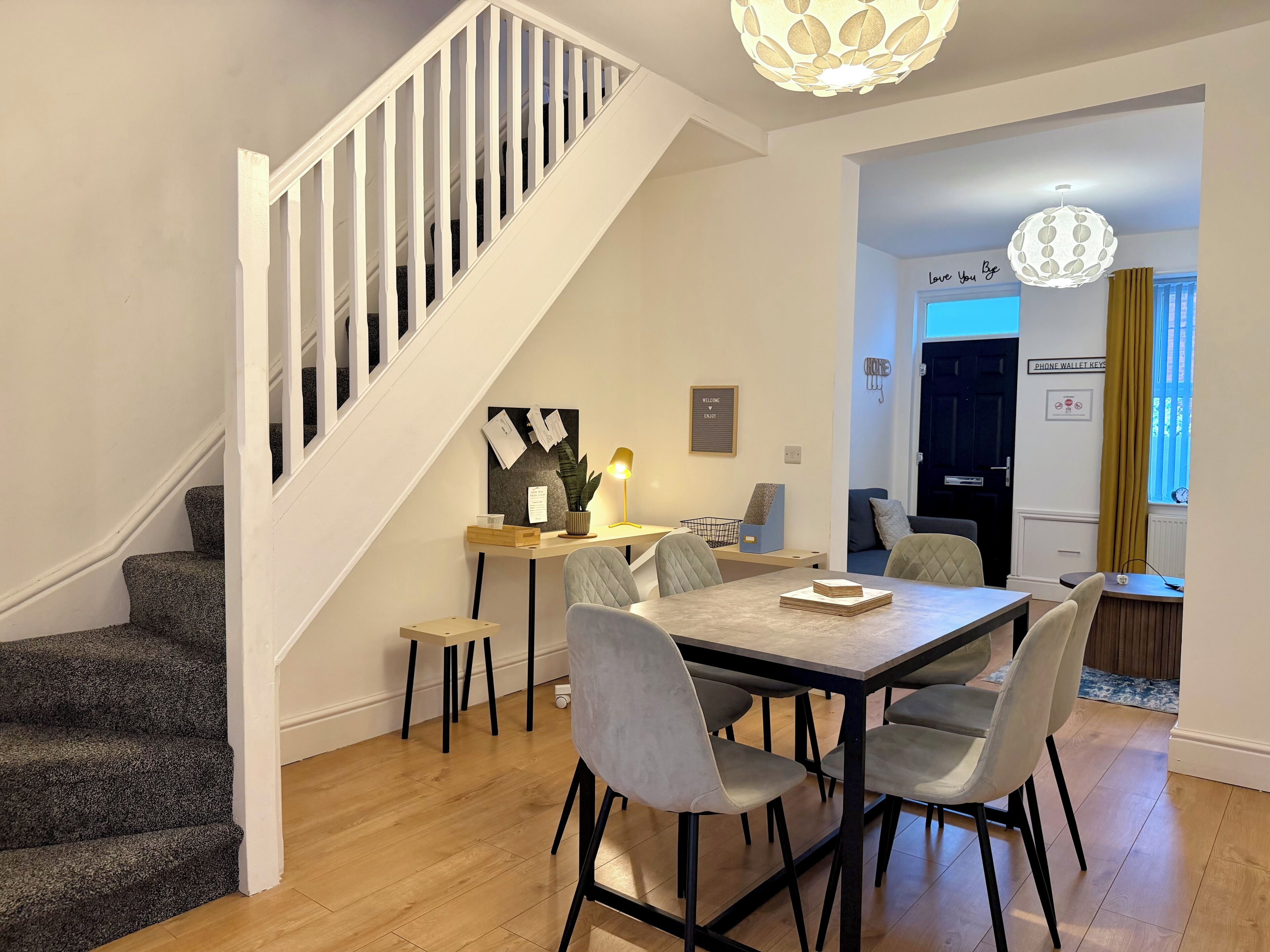A modern interior with a staircase, a dining area with a table and chairs, and a living space with a sofa.