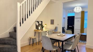 A modern interior with a staircase, a dining area with a table and chairs, and a living space with a sofa.