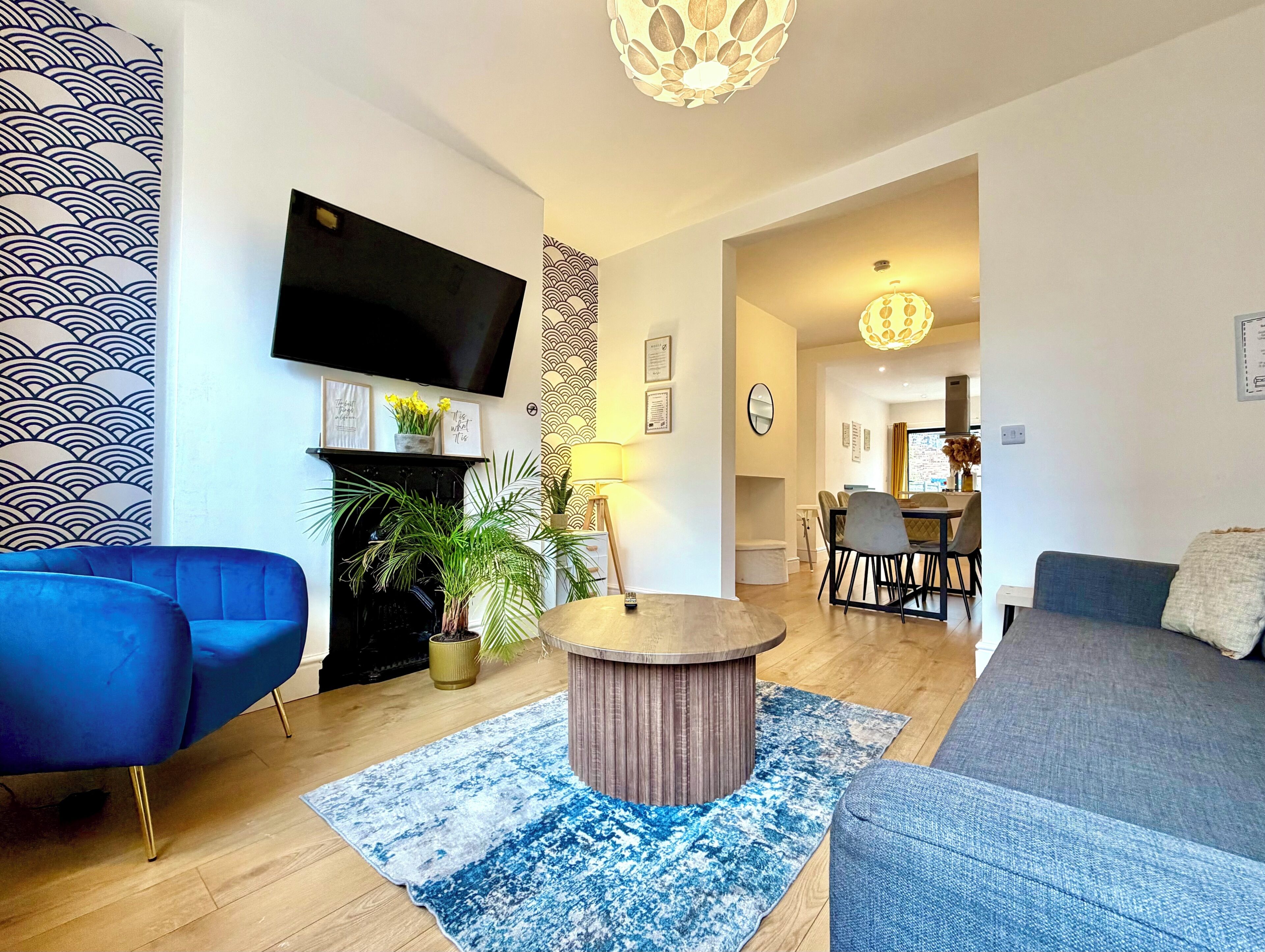 Una sala de estar moderna con un televisor de pantalla plana, una chimenea y un comedor con mesa y sillas.