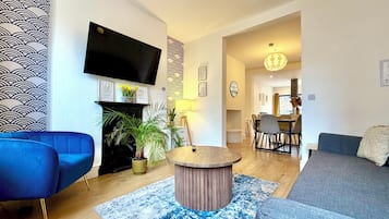 Una sala de estar moderna con un televisor de pantalla plana, una chimenea y un comedor con mesa y sillas.