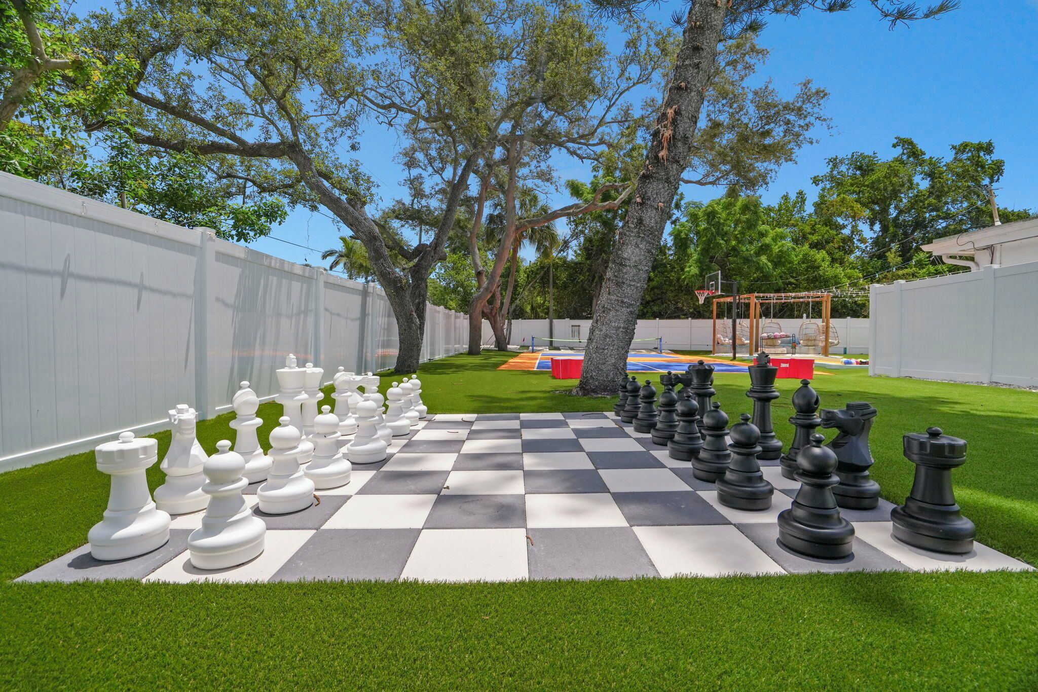 A chessboard set up on a grassy lawn with trees in the background.