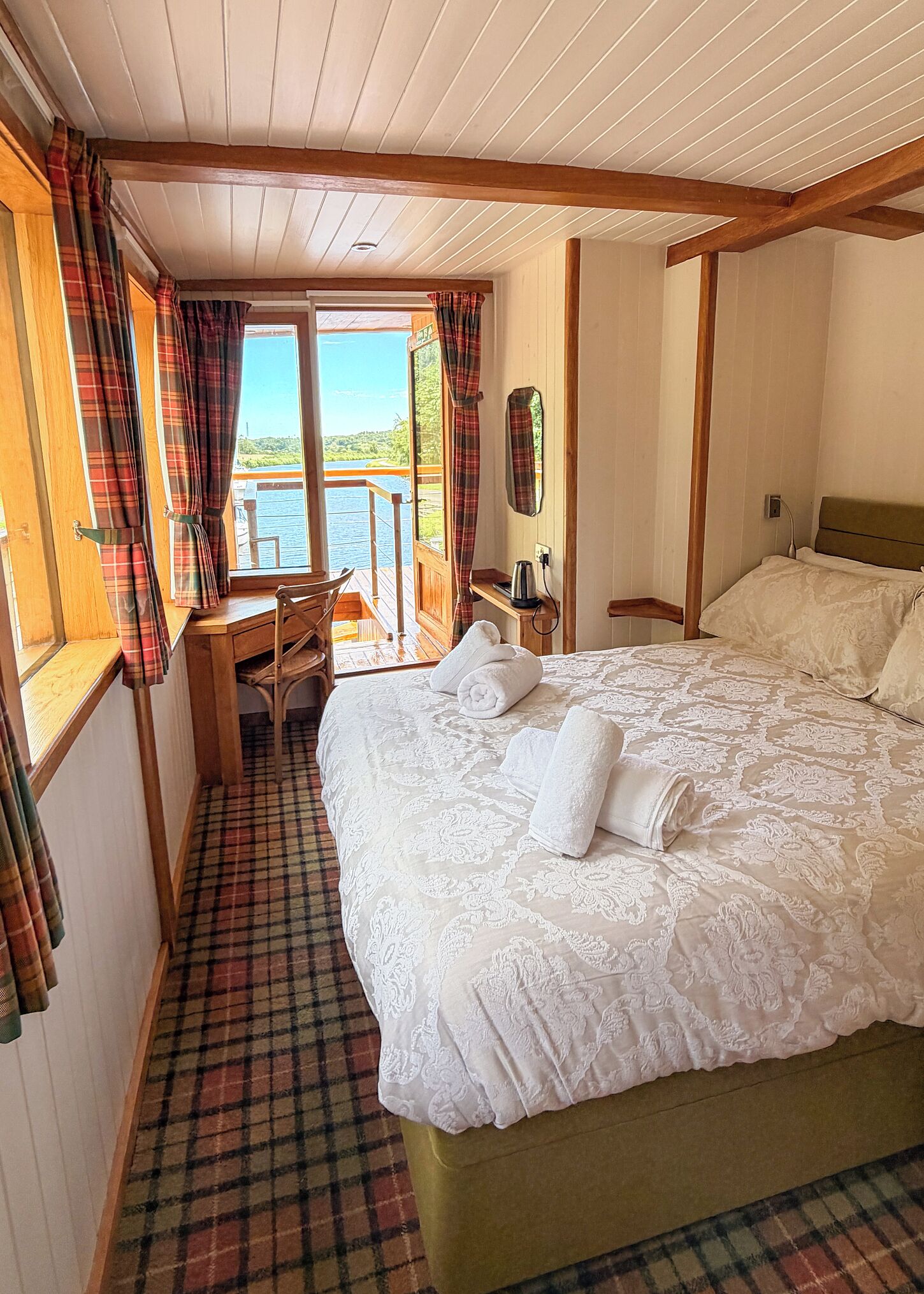 Un dormitorio con una cama, un escritorio y vistas a un cuerpo de agua.