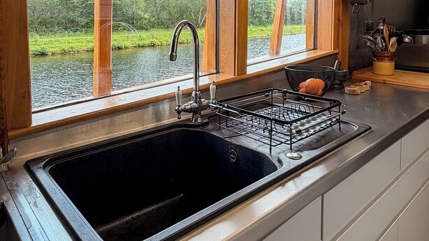 A kitchen with a large window, a sink, and a stove.