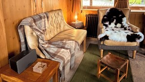 A cozy room with a sofa, a chair, a table, and a radiator.