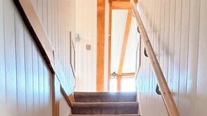 A carpeted staircase with wooden handrails and a white wall with vertical lines.