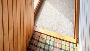 A wooden door leading to a room with a carpeted floor and a view of the outdoors.