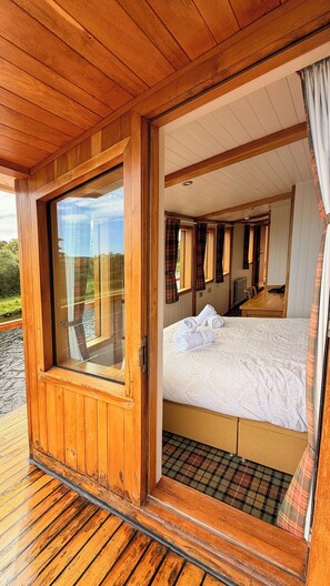 A wooden cabin with a bed, a window, and a view of the outdoors. - Highland Lassie: A Historic Yacht in the Heart of the Scottish Highlands (Inverness)