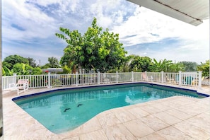 A swimming pool with a white fence, surrounded by a tiled deck and lush greenery. - Canal Paradise Pool, Kayaks, BBQ & Firepit (Port Charlotte)