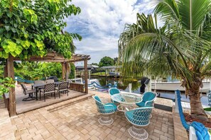An outdoor patio with a pergola, seating, and a view of a body of water. - Canal Paradise Pool, Kayaks, BBQ & Firepit (Port Charlotte)