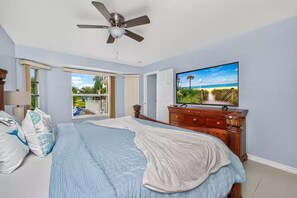 A bedroom with a bed, a television, a ceiling fan, and a view of the outdoors. - Canal Paradise Pool, Kayaks, BBQ & Firepit (Port Charlotte)