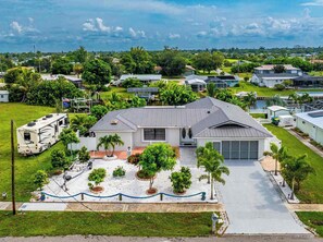 A single-story house with a garage, surrounded by a well-maintained lawn and several trees. - Canal Paradise Pool, Kayaks, BBQ & Firepit (Port Charlotte)