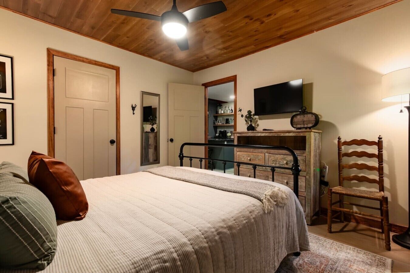 A bedroom with a bed, a dresser, a chair, a ceiling fan, and a television.