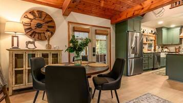 A dining area with a round table, chairs, and a wall clock.