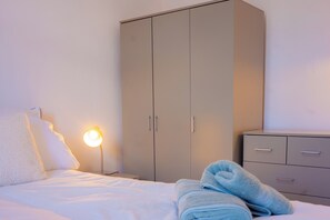 A bedroom with a bed, a wardrobe, and a bedside lamp. - 27 Agnes Street (Manchester)