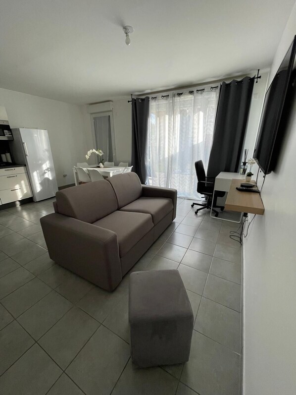 Een moderne woonkamer met een bank, een bijzettafeltje en een bureau met stoel.