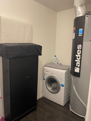 Een kleine wasruimte met een wasmachine, een droger en een koelkast.