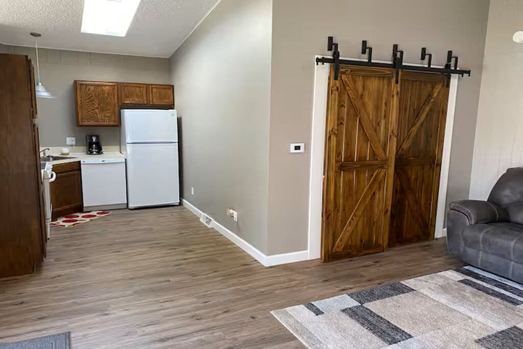 Un espacio habitable compacto con cocina, una puerta corredera estilo granero y un sofá.