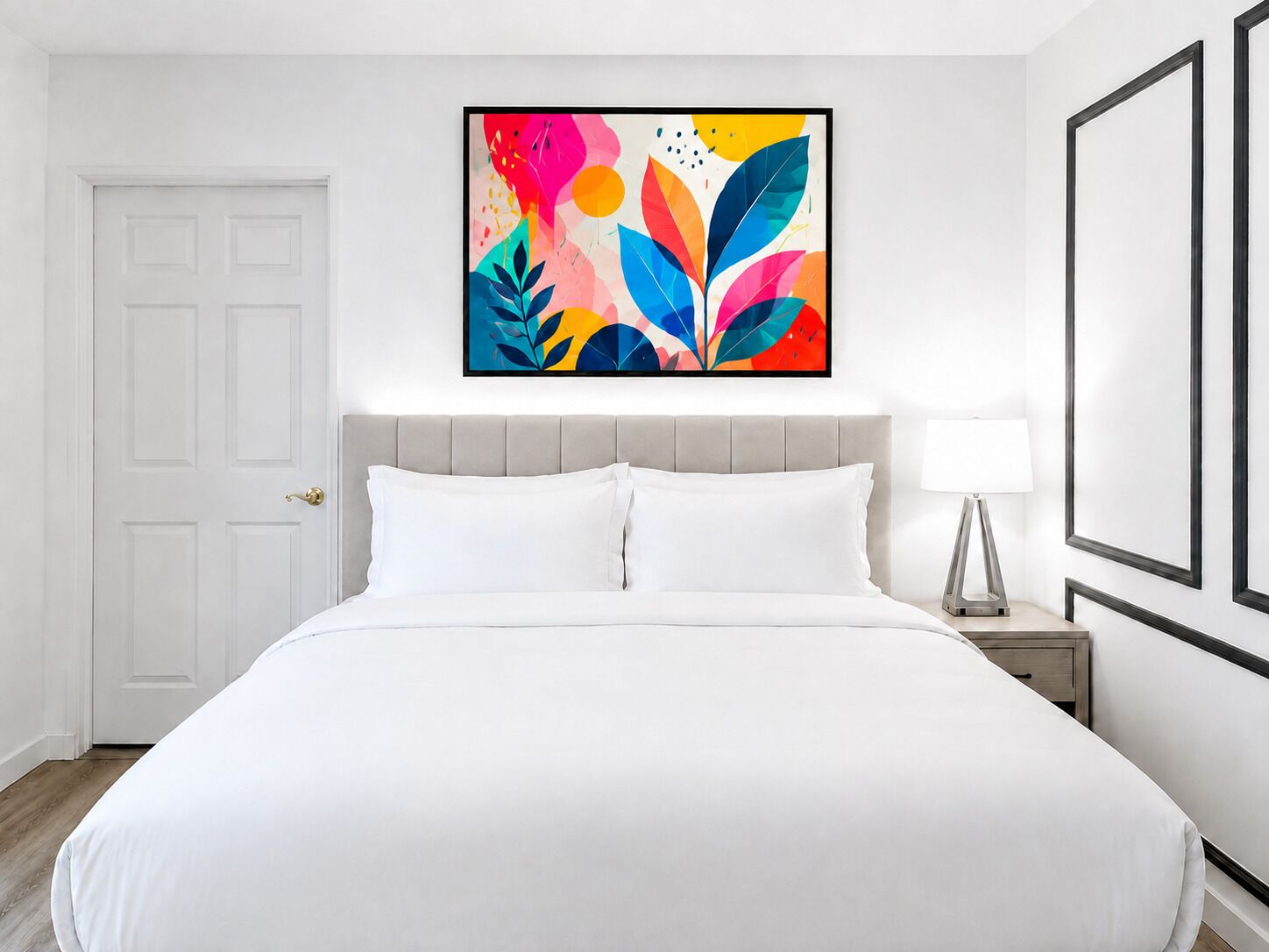 Una camera d'albergo con un letto, un comodino, una lampada e un quadro astratto dai colori vivaci appeso al muro.