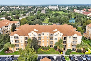 A multi-story residential building with a central courtyard, surrounded by greenery and a parking lot. - *The Fairytale Condo*  2 Miles to Disney (Kissimmee)