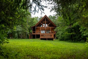 Eine Holzhütte mit Balkon, umgeben von üppigem Grün.